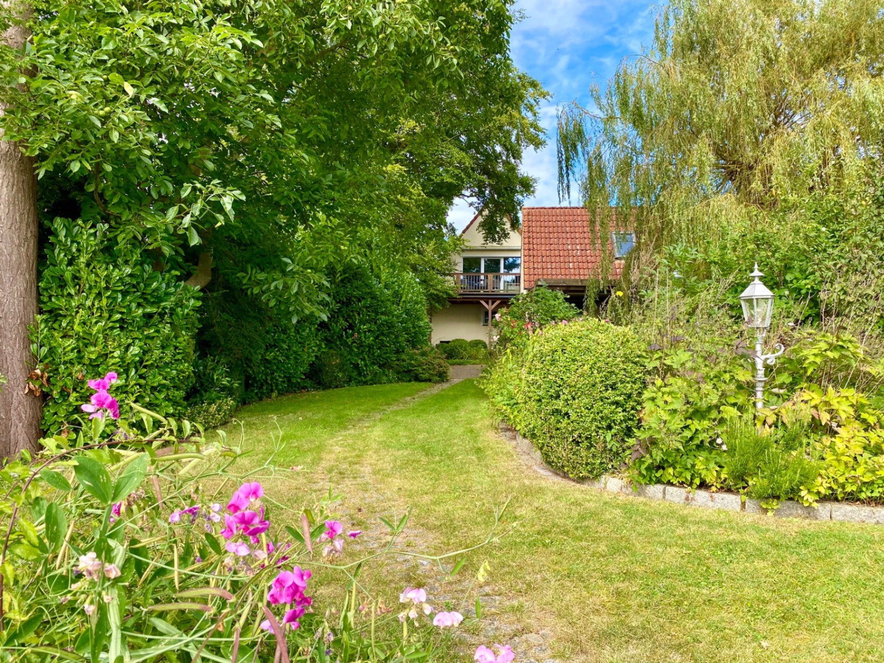 Gepflegter Garten mit Blumen und Blick auf das Ferienhaus