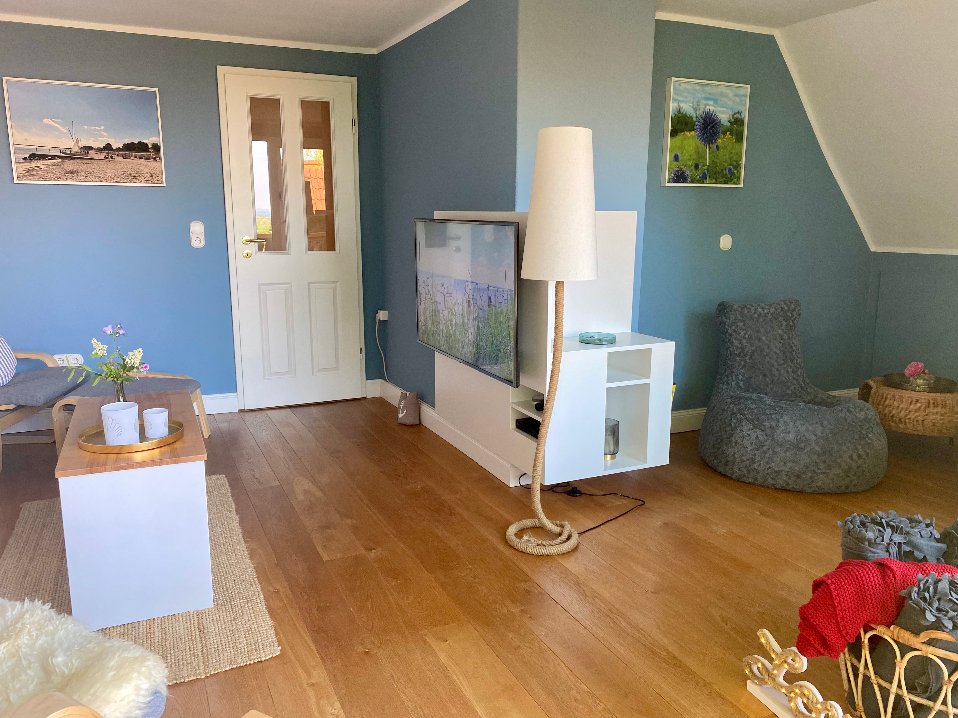 Helles Wohnzimmer mit blauen Wänden, Smart-TV, Stehlampe und Sitzsack