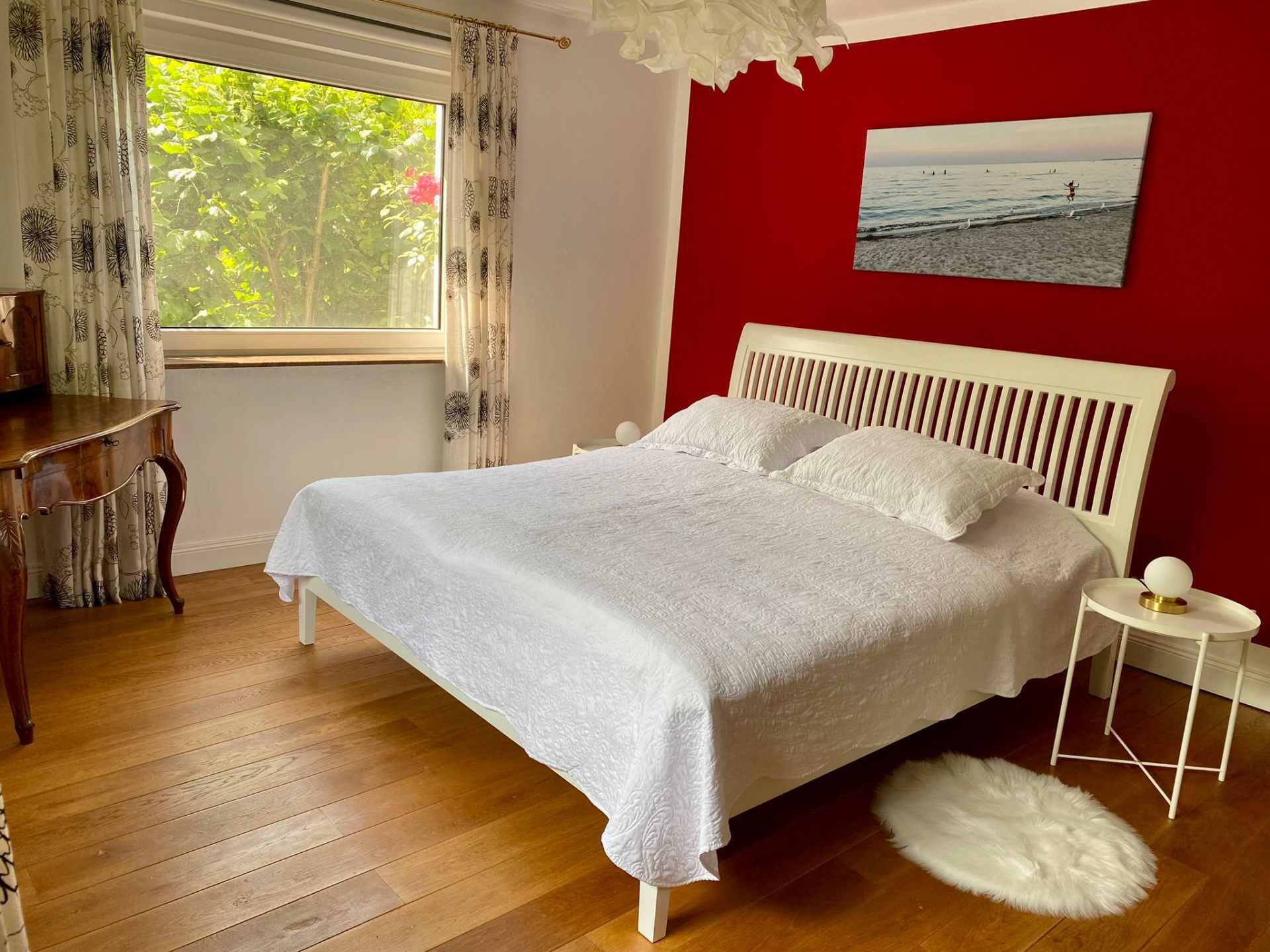 Schlafzimmer mit weißem Bett und roter Wand
